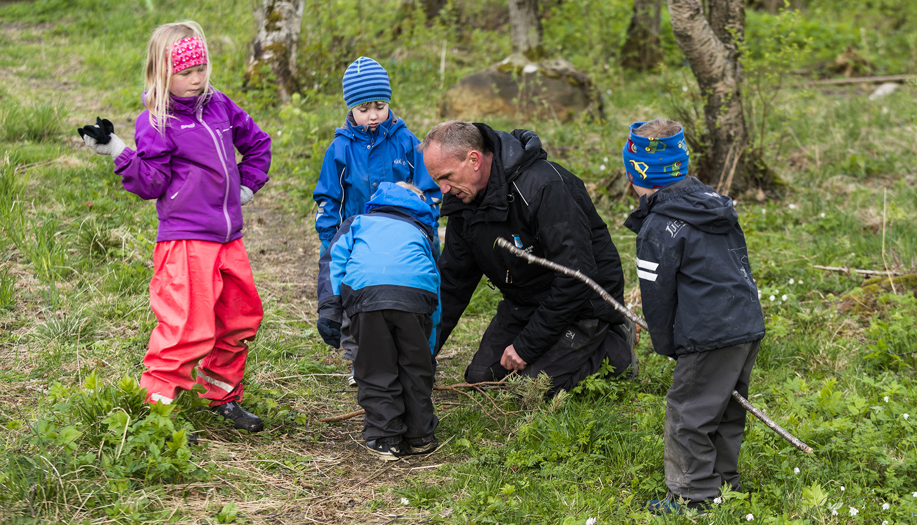 Barnehagelærer og fire barn på tur i skogen