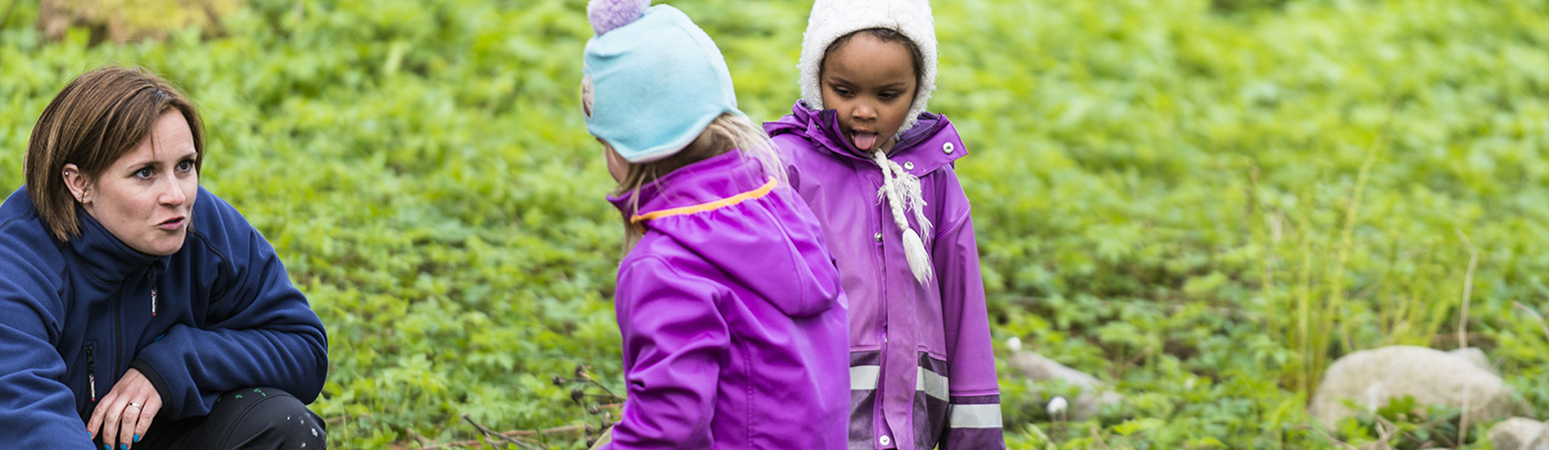Barnehagelærer og to barn på tur i skogen