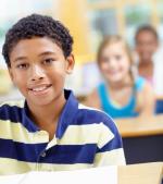 Gutt sitter ved pulten i klasserommet